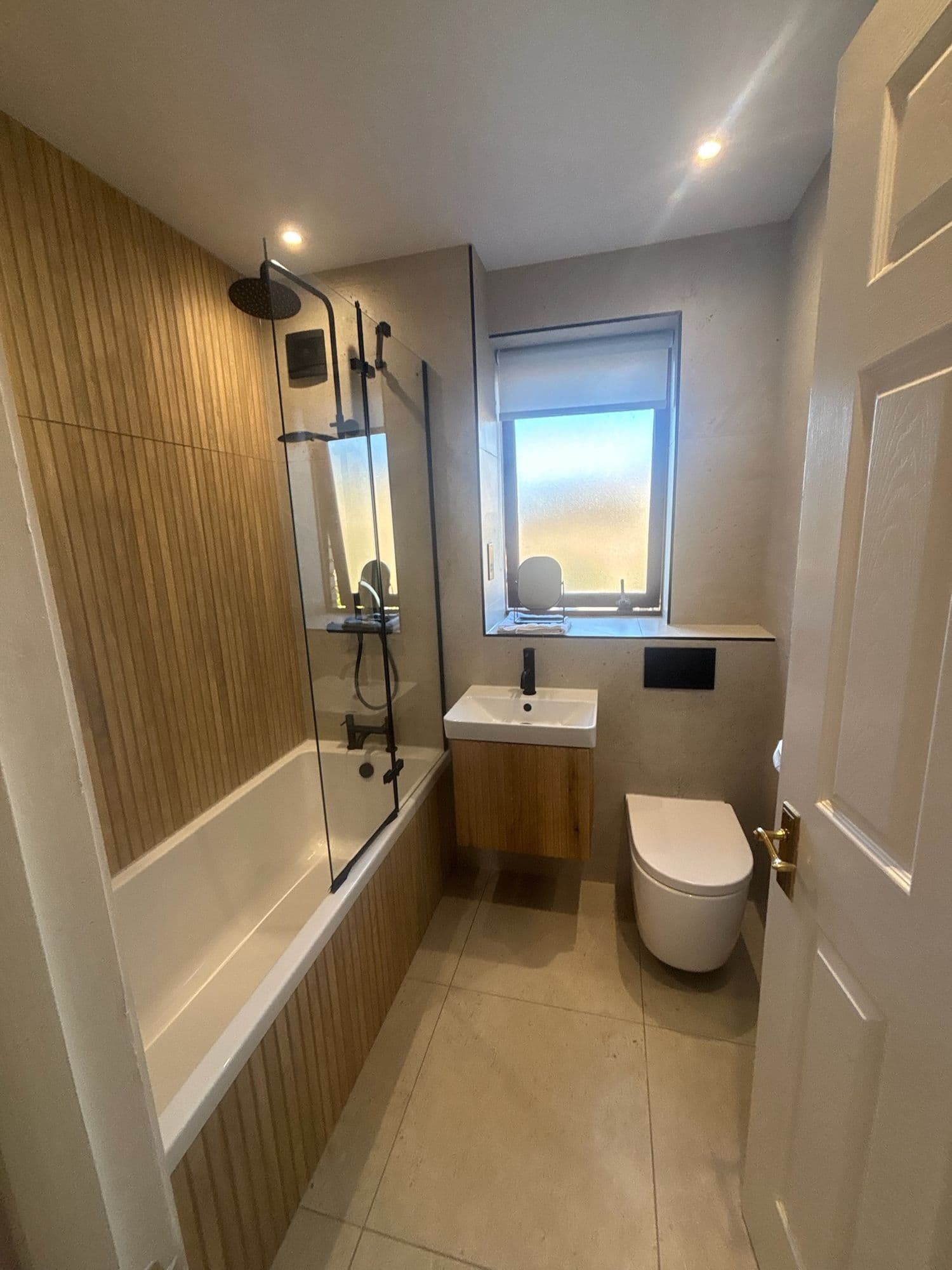Modern bathroom with bath, shower and timber panelling