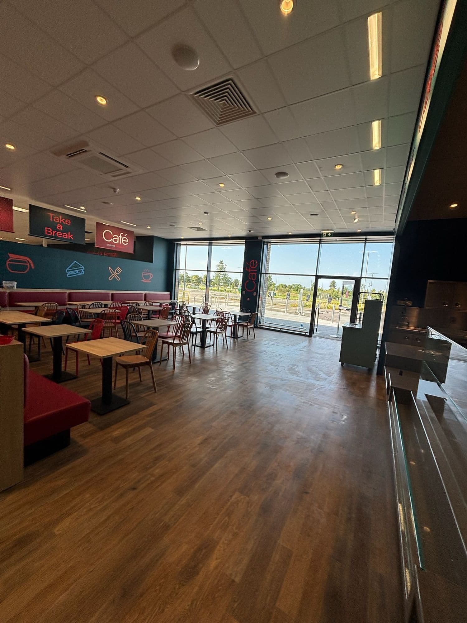 Bright café dining area with wooden floor, booth seating and floor-to-ceiling windows