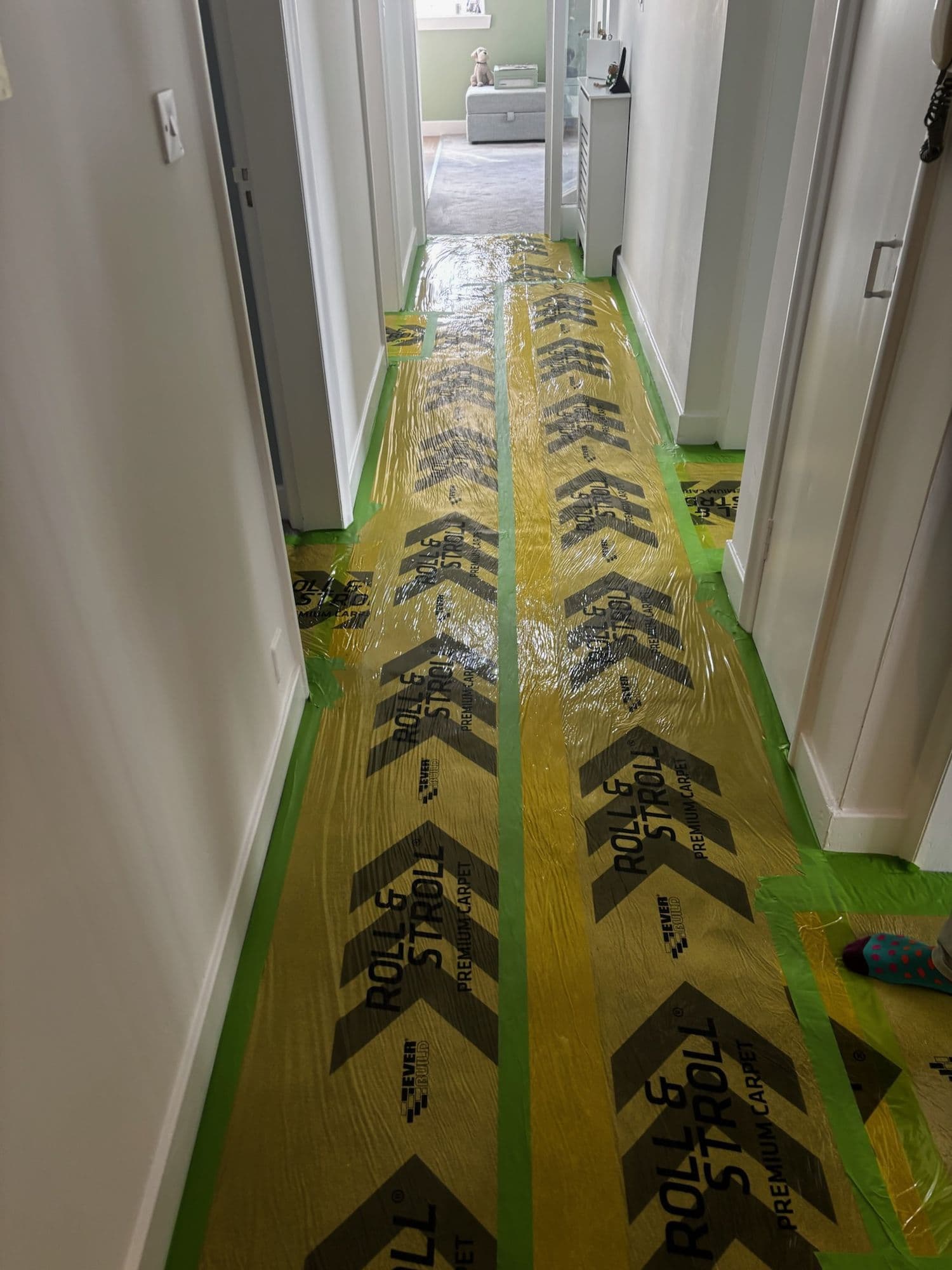 Hallway carpet covered with self-adhesive protection film and taped edges