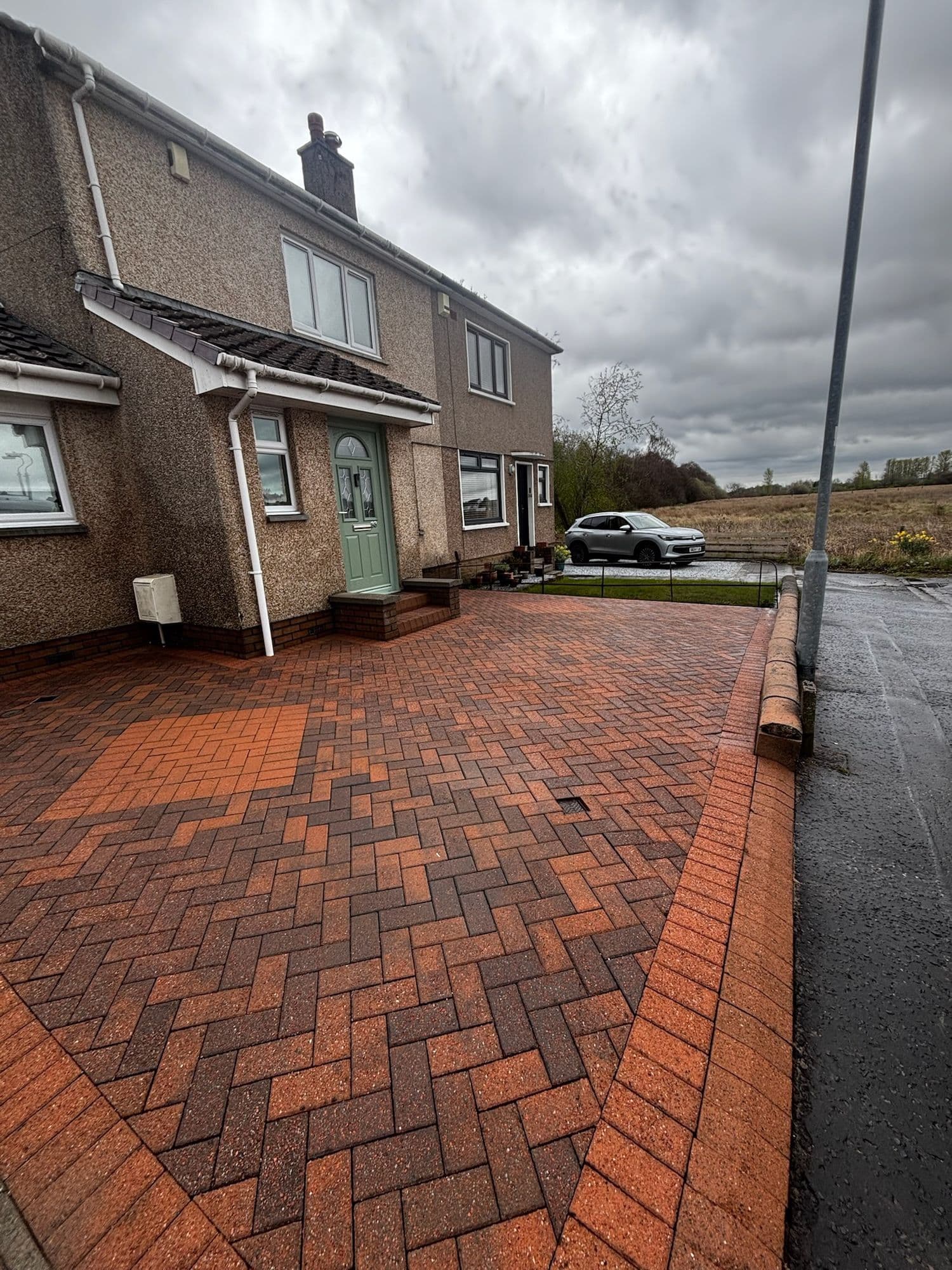 After: The same driveway after restoration, the red herringbone block paving clean and bright