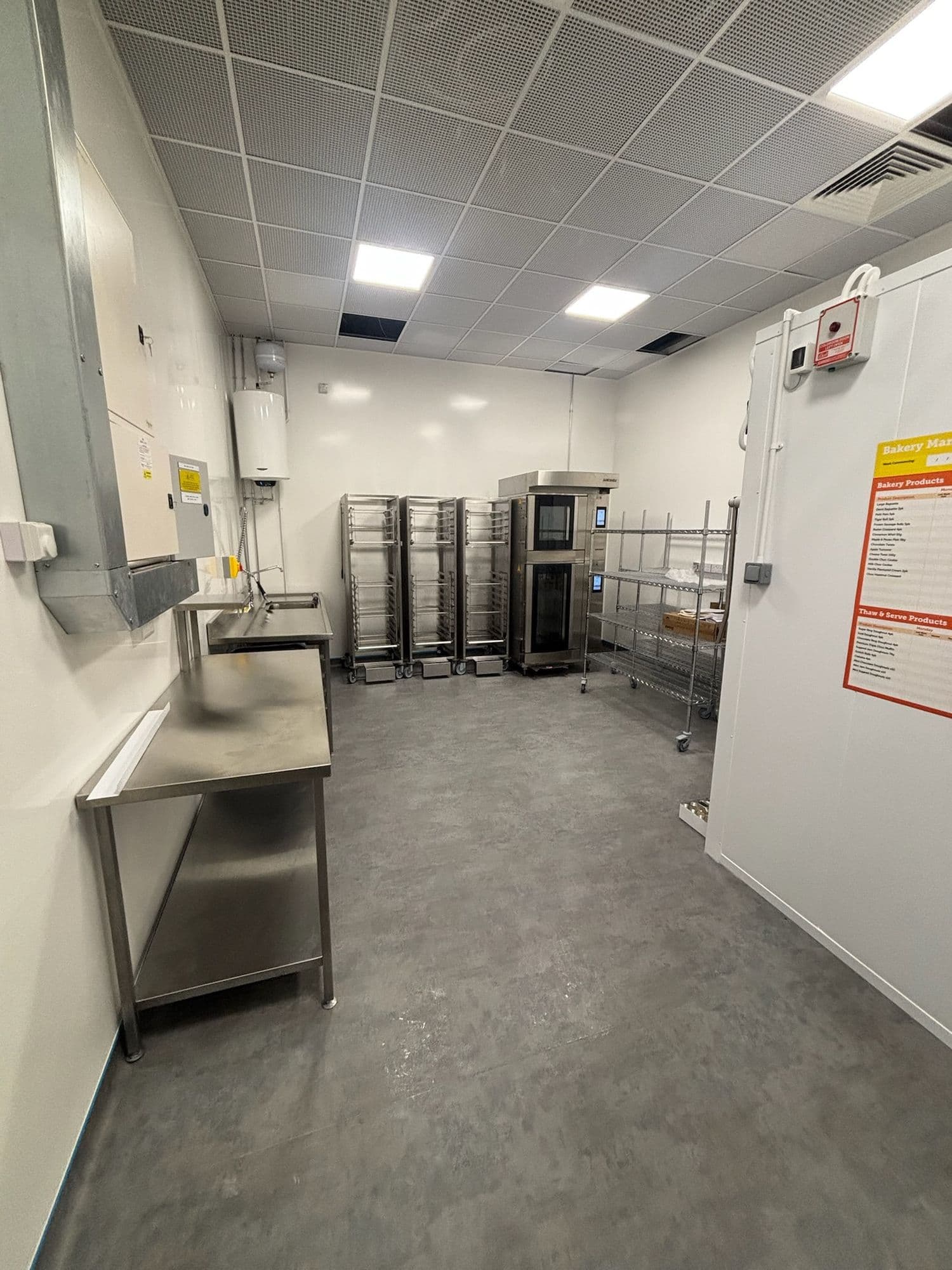 Commercial kitchen prep room with stainless worktops, oven racks and a walk-in chiller