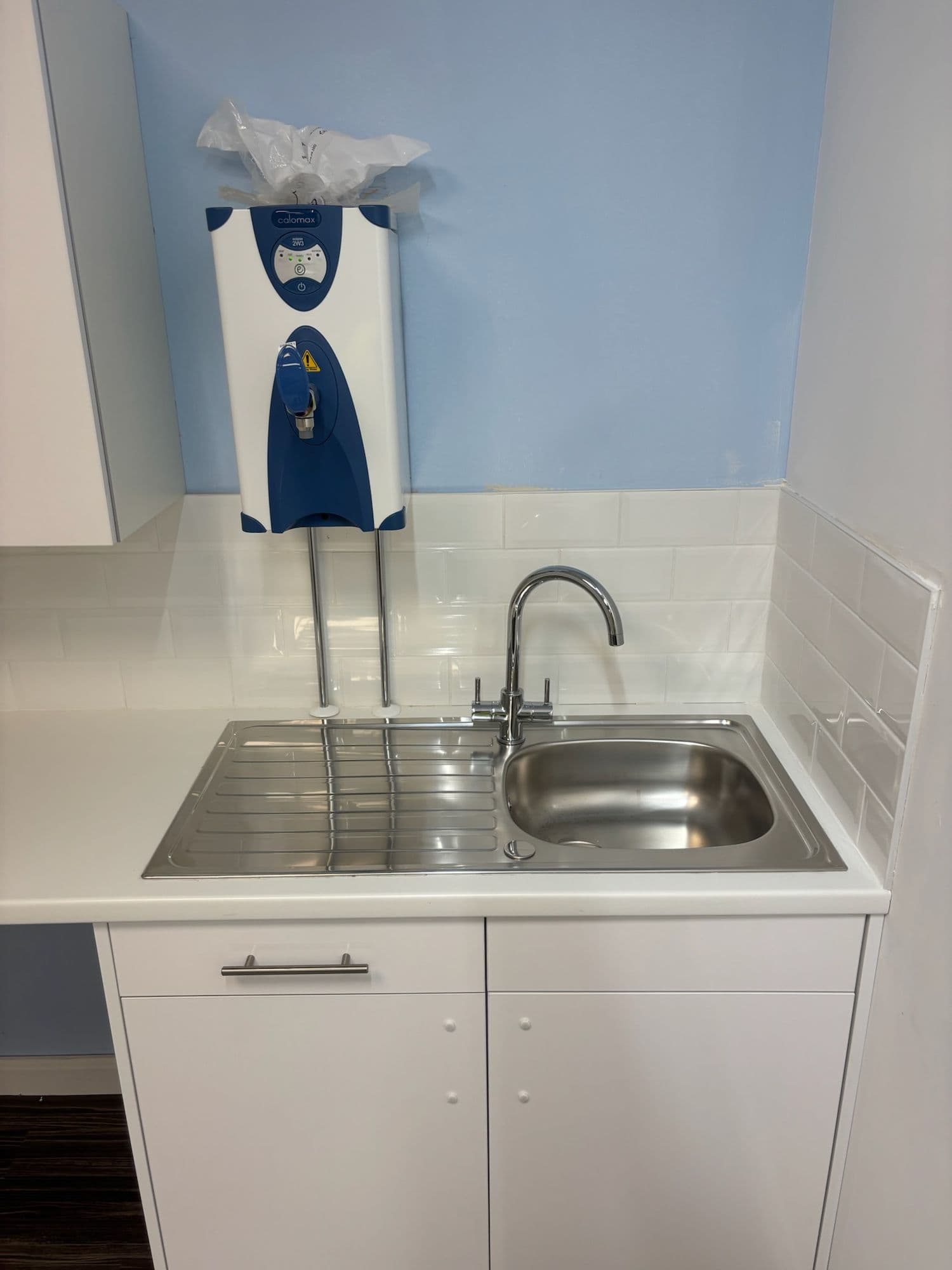 Office kitchenette with white units, steel sink and water heater
