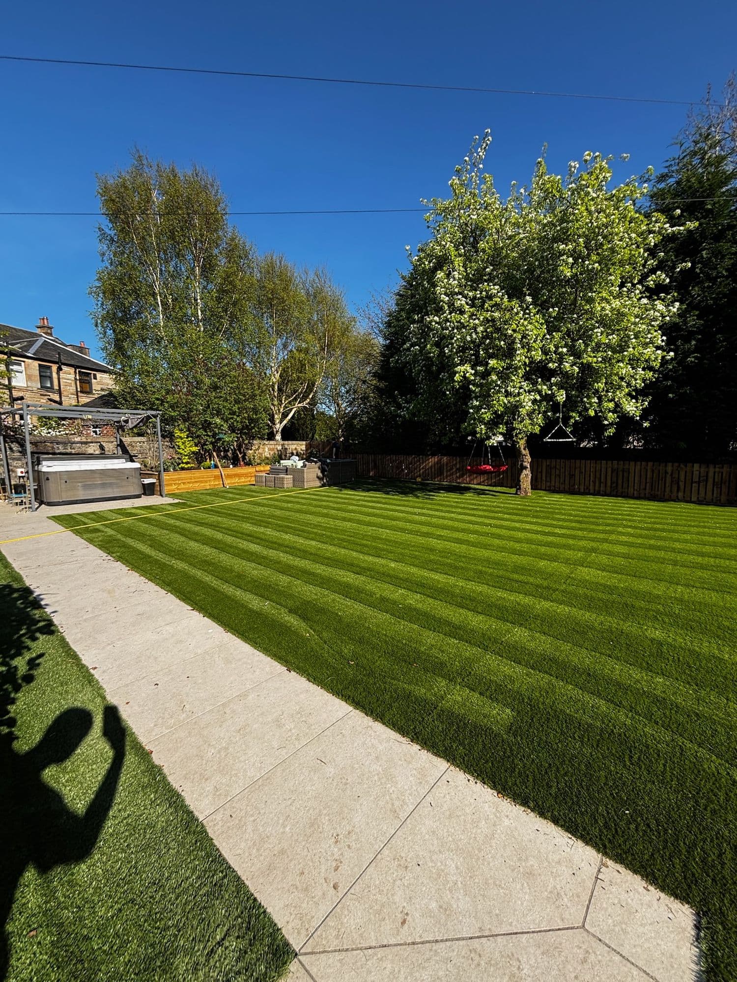 Freshly striped lawn beside a paved path under a clear blue sky
