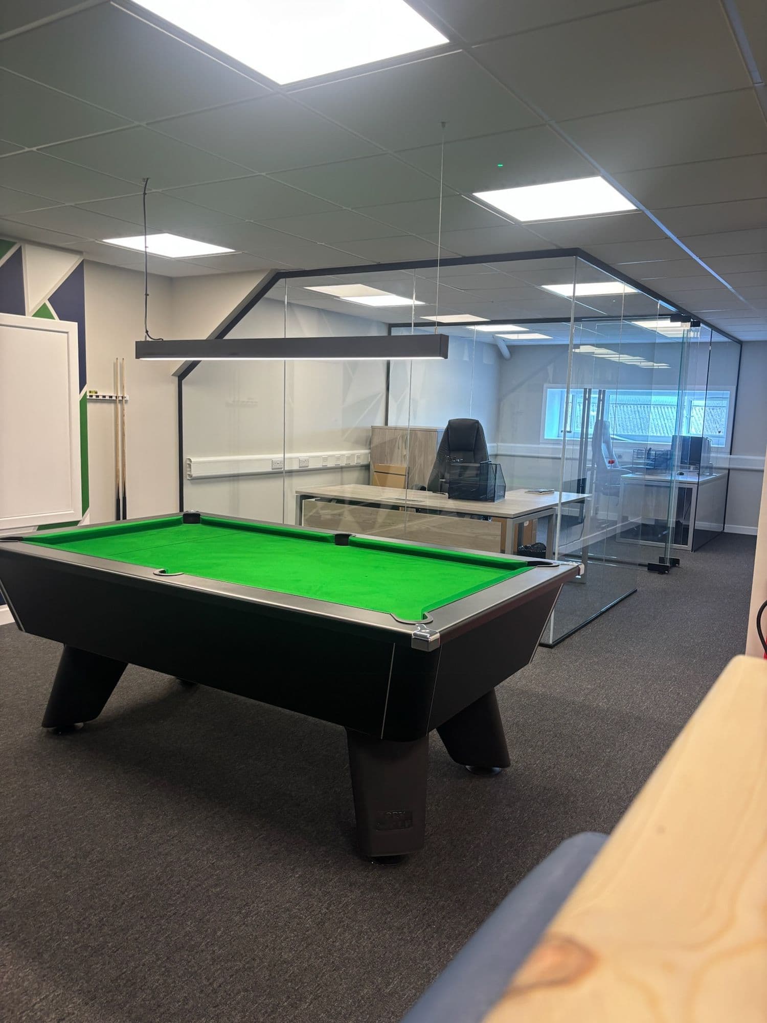 Office breakout area with a pool table beside glass-walled meeting rooms