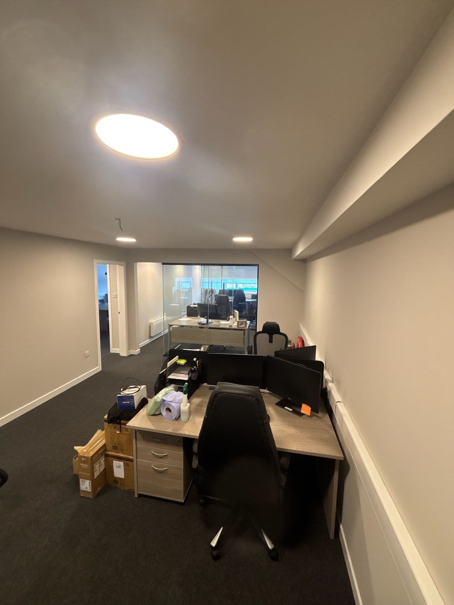 Open office with desks and monitors under recessed lights