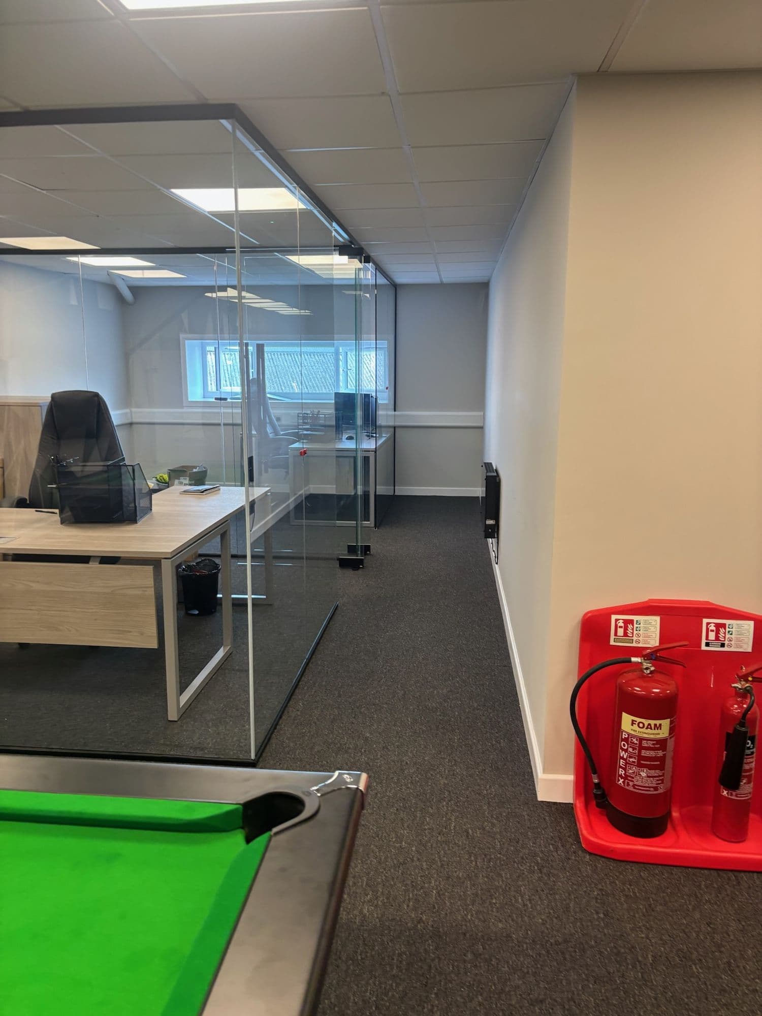 Office floor with glass partitions, a desk and a fire extinguisher station