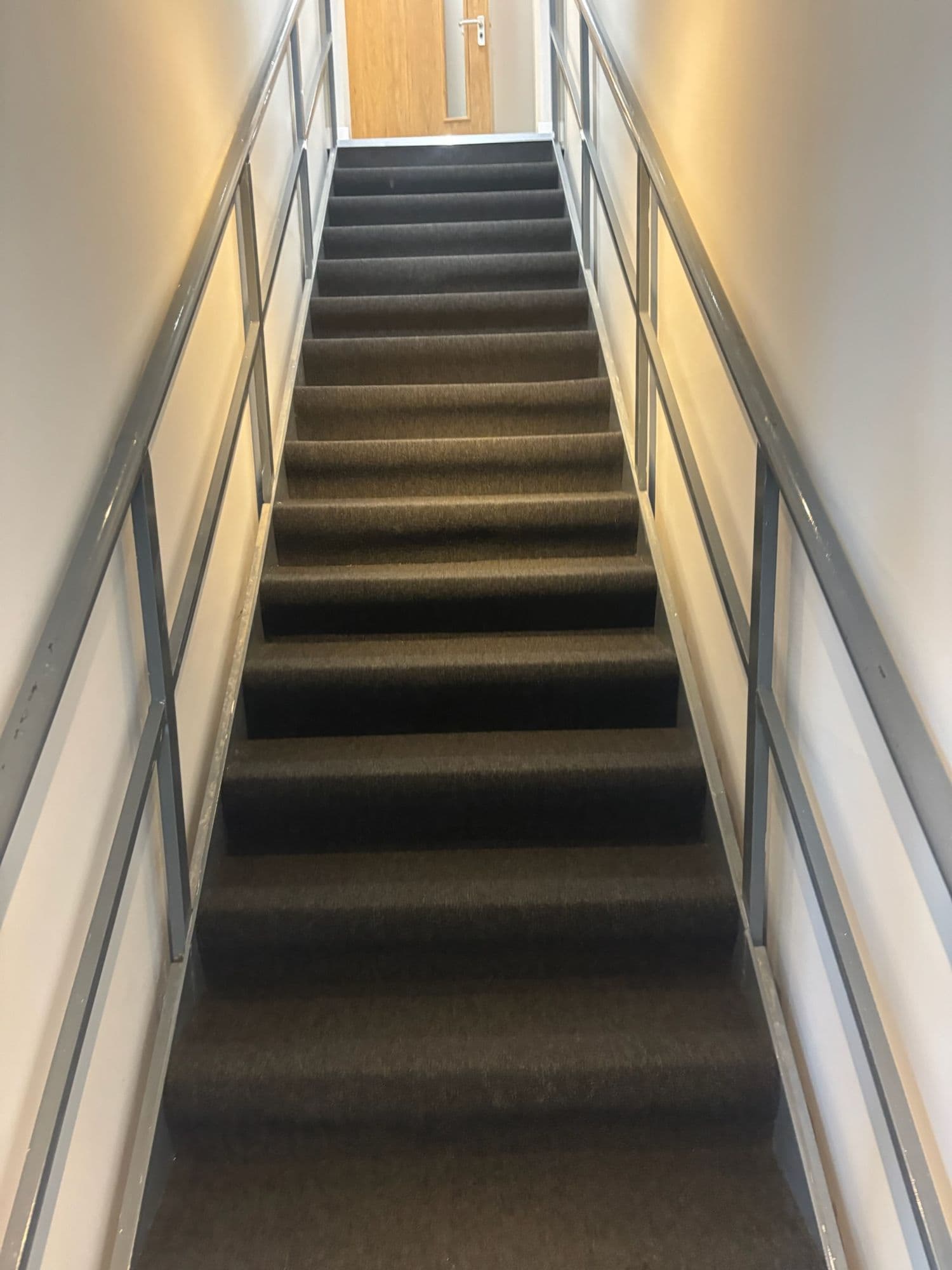 Carpeted staircase with metal handrails between office floors