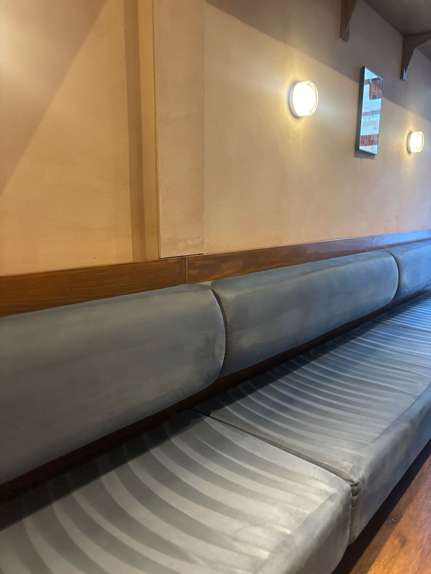 Grey upholstered banquette seating along a restaurant wall