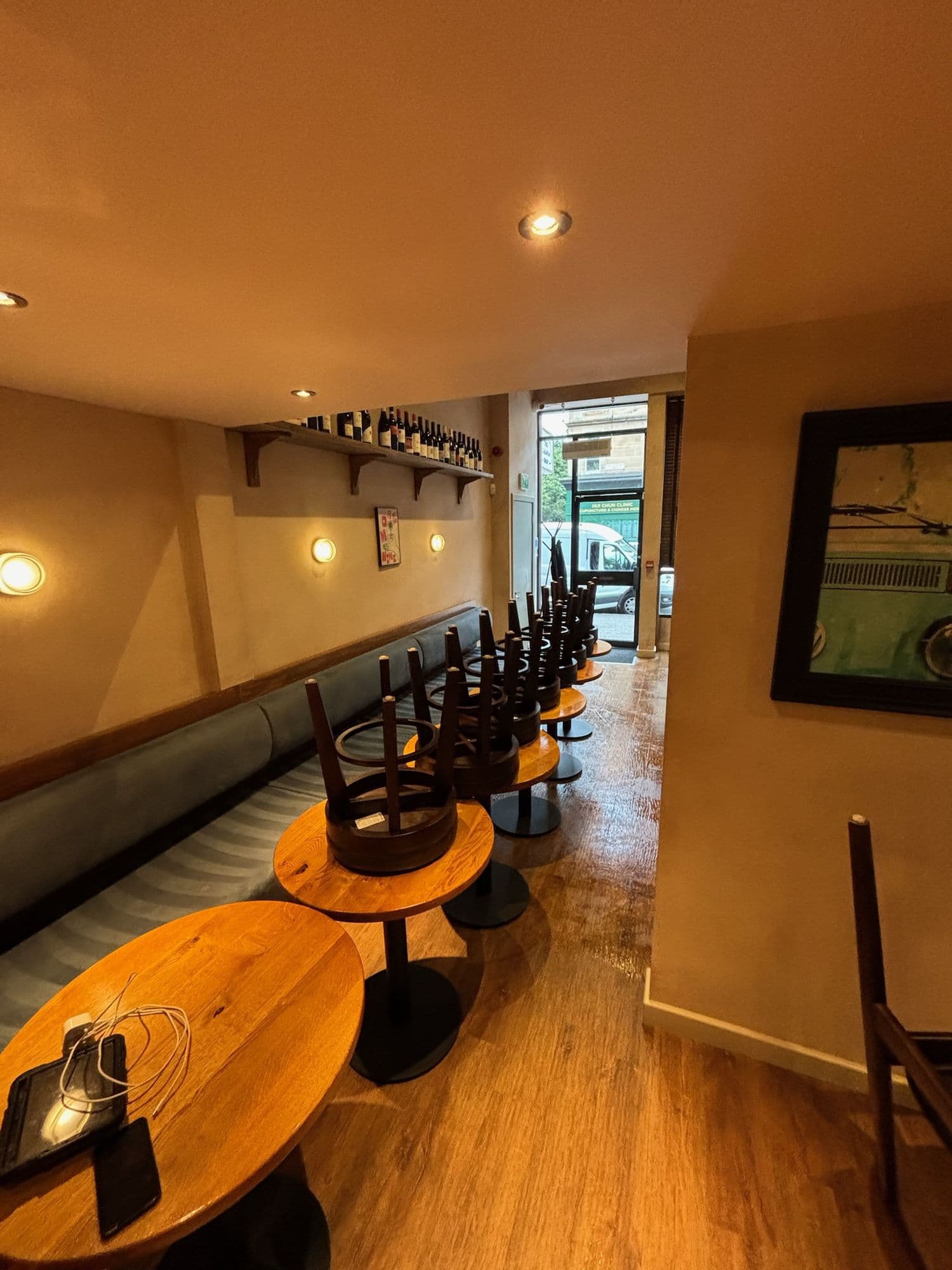 Restaurant dining room with round wooden tables and chairs stacked for cleaning