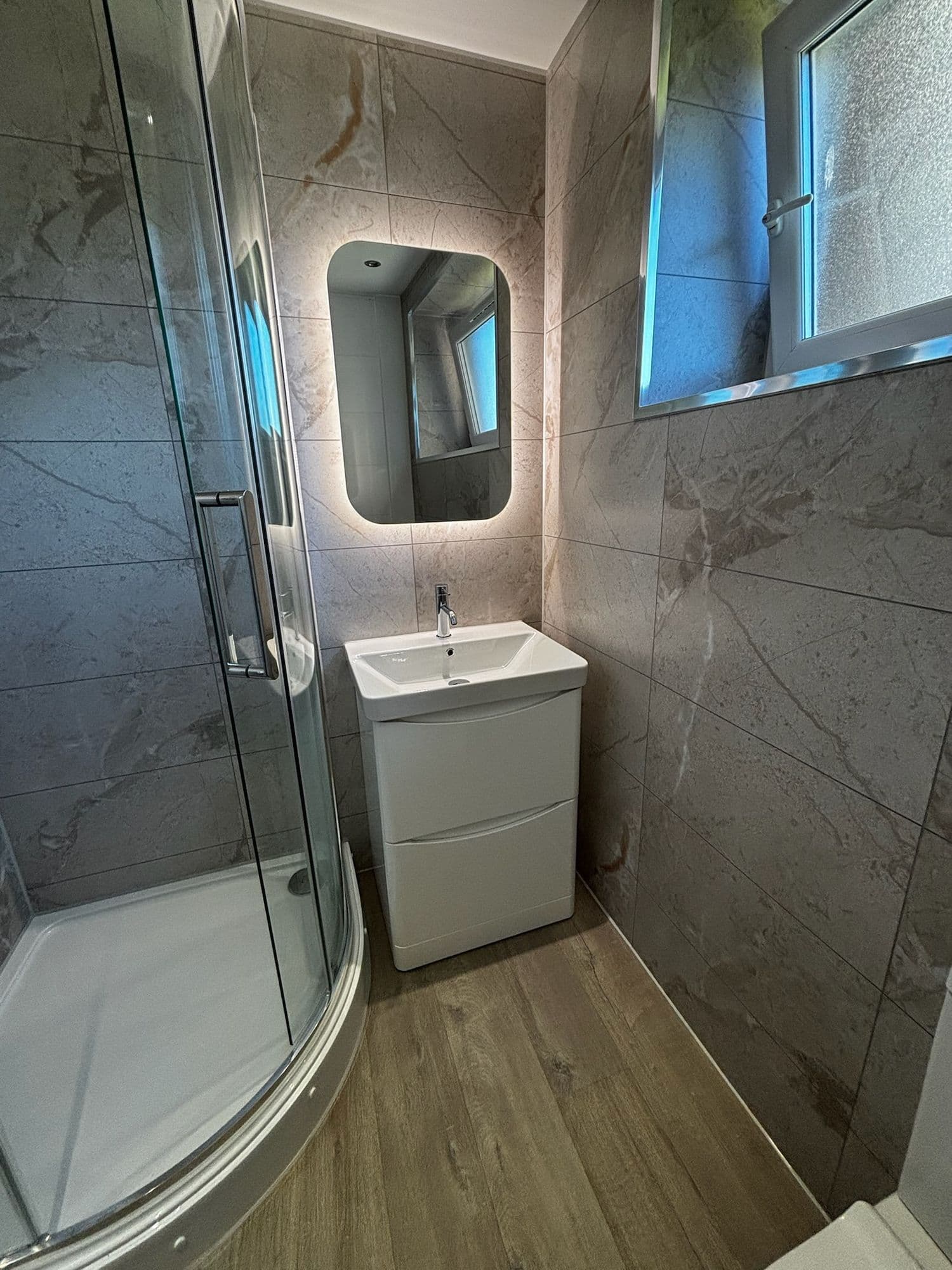 Bathroom with quadrant shower, illuminated mirror and vanity unit