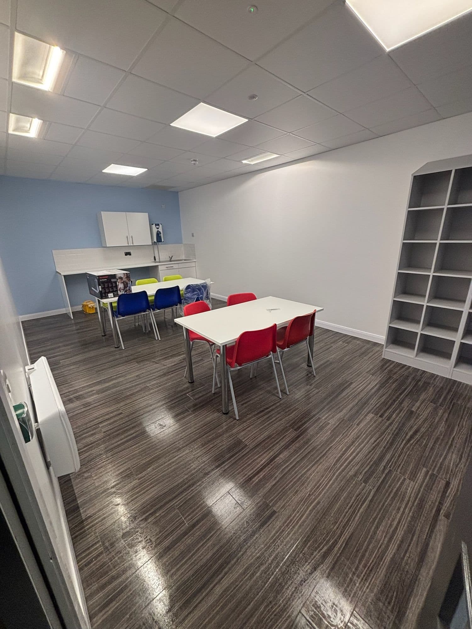 Staff room with red and white tables and polished wood-effect floor