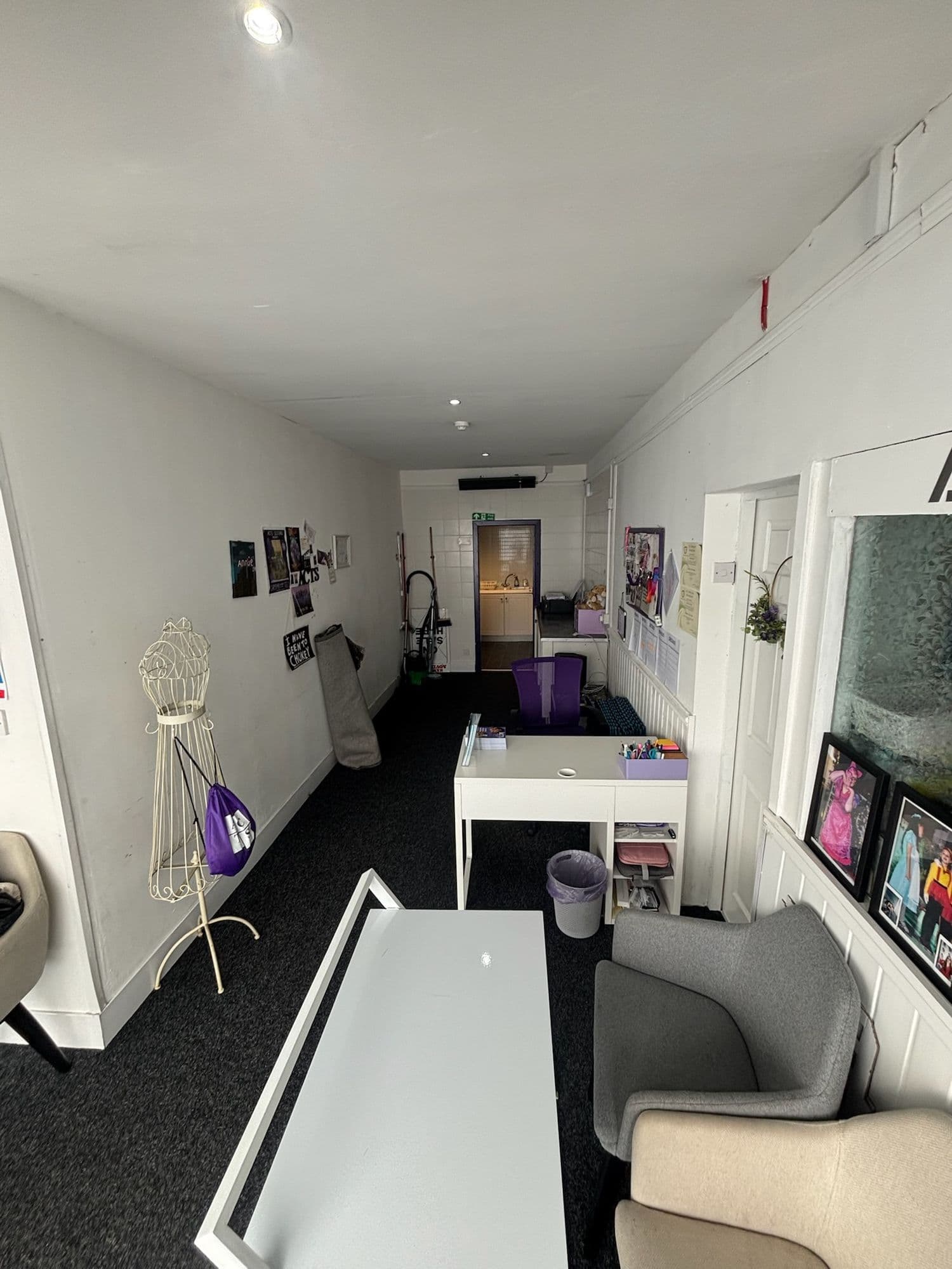 Long reception corridor with seating, a white desk and a wall screen